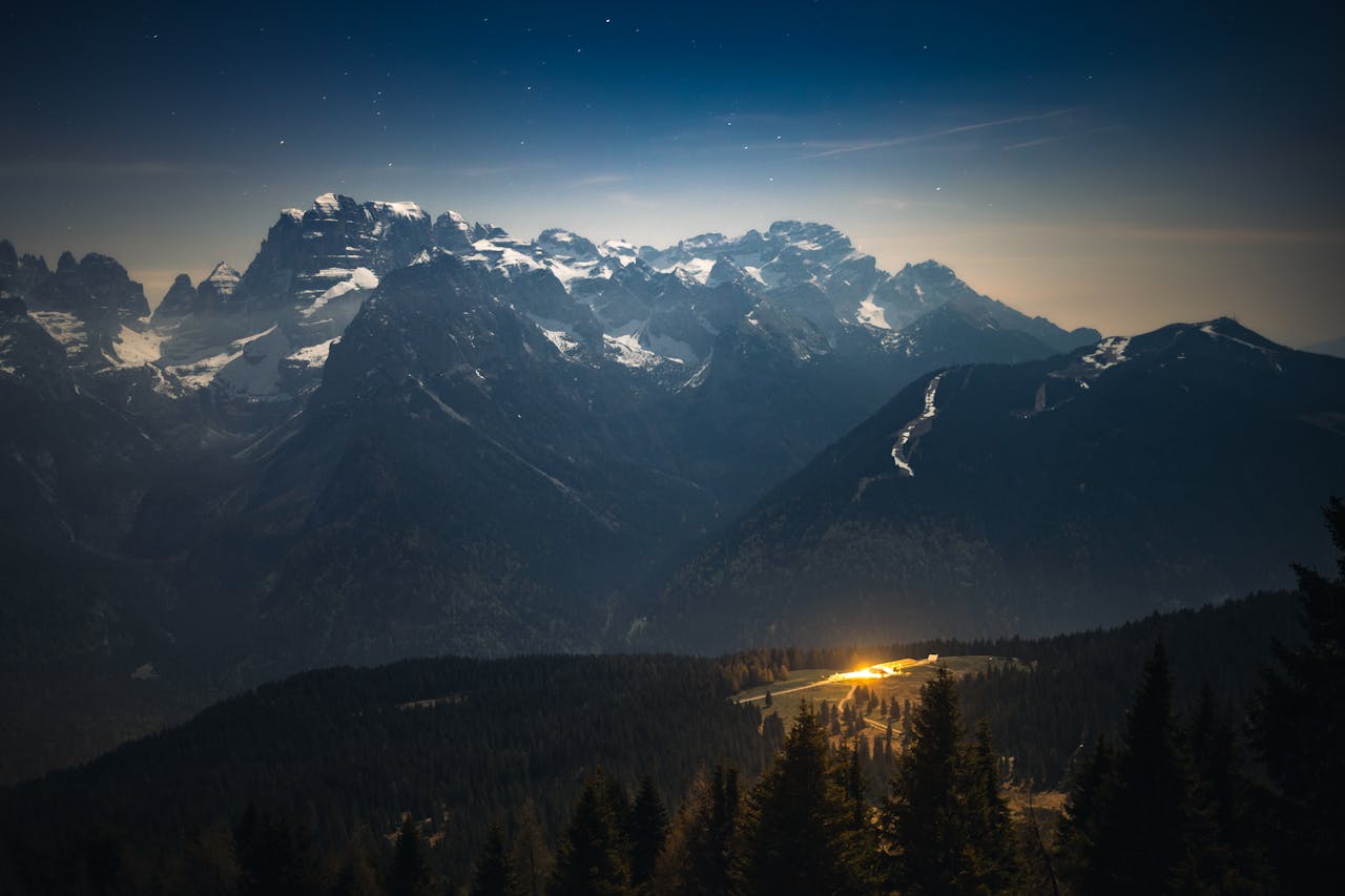 Stunning astrophotography showcasing the Milky Way over snow-capped Italian Alps at night.